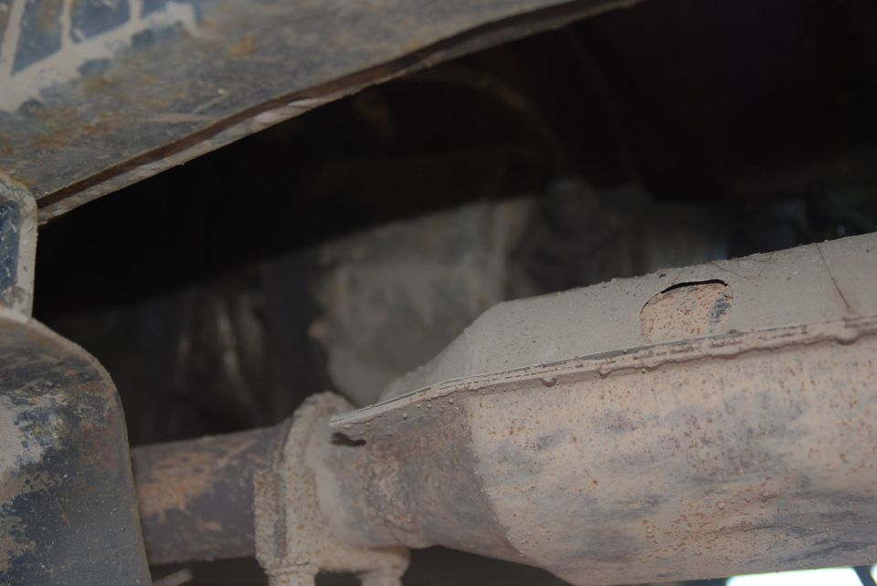 Underside of a vehicle showing exhaust pipe and frame components. Watermark says SUPERMOTORS.NET
