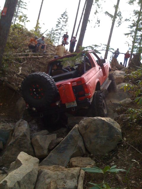 1989 Ford Bronco - Red 1989 Ford Bronco tackling a difficult rocky obstacle on an off-road trail.