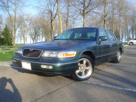 1996 Mercury Grand Marquis - Green 1996 Mercury Grand Marquis with aftermarket wheels parked in a lot.