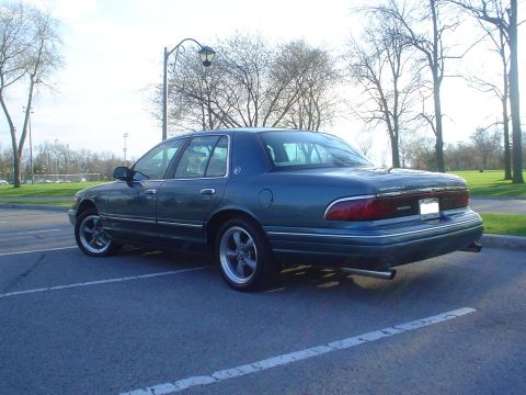 1996 Mercury Grand Marquis - This Mercury Grand Marquis is parked in a lot with trees in the background.