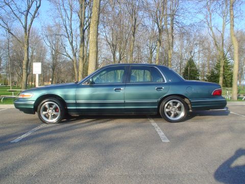1996 Mercury Grand Marquis - A green sedan is parked in a lot with trees in the background.