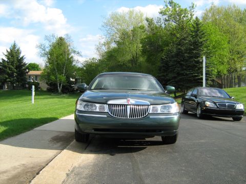 1988 Mercury Grand Marquis - Two sedans are parked on a residential street on a sunny day.