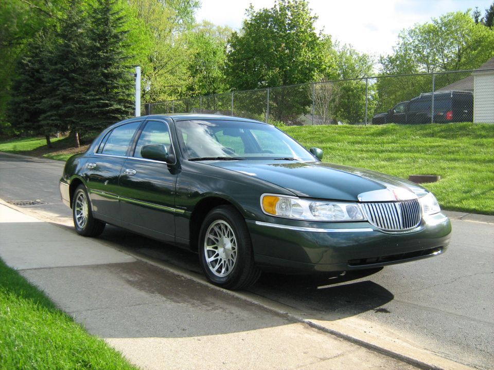 Dark green Lincoln Town Car parked on a residential street. Chrome grille and trim visible