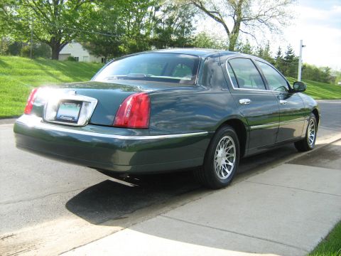 1988 Mercury Grand Marquis - Rear view of a dark green sedan parked on a residential street with trees in the background.