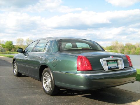 1988 Mercury Grand Marquis - Rear view of a green sedan parked outdoors with a lake in the background.