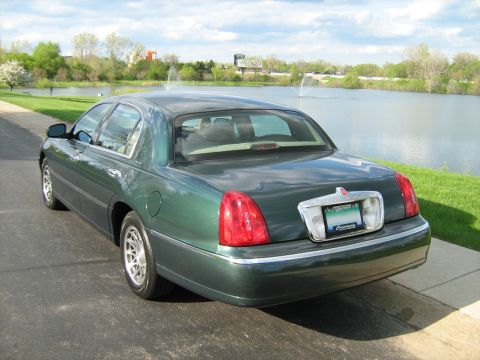 1988 Mercury Grand Marquis - Green Lincoln Town Car parked outdoors with a lake and fountain in the background.
