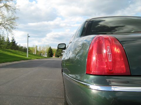 1988 Mercury Grand Marquis - The taillight of a green sedan is visible with a cloudy sky in the background.
