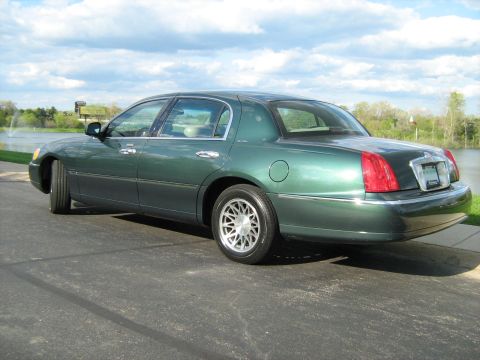 1988 Mercury Grand Marquis - Green sedan parked on asphalt with a lake and trees in the background.