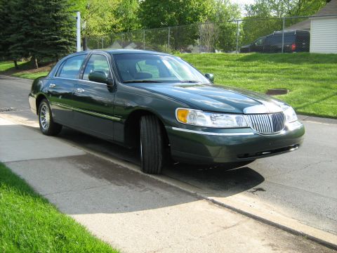 1988 Mercury Grand Marquis - A dark green Lincoln Town Car is parked on the side of a residential street.