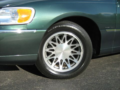 1988 Mercury Grand Marquis - The front passenger side of a green sedan, a distinctive alloy wheel and 'Town Car' badging on the fender.
