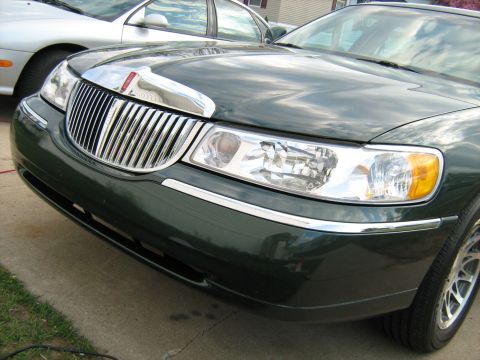 1988 Mercury Grand Marquis - The front of a dark green Lincoln Town Car is visible, with a chrome grille and headlights.