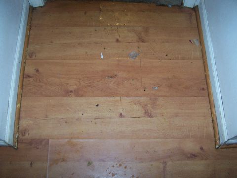 1978 Ford Bronco - A close-up view of a worn wooden floor with visible dirt and scuffs.