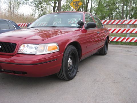 2000 Ford Crown Victoria - Red 2000 Ford Crown Victoria parked on a paved surface, with another vehicle partially visible to the left.