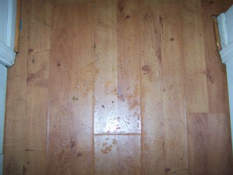 1978 Ford Bronco - A close-up view of a worn wooden floor with visible damage and debris.