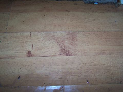 1978 Ford Bronco - A close-up view of a wooden floor shows the natural grain patterns and scattered debris.