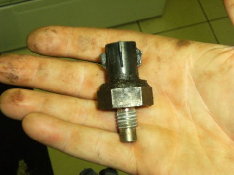 1990 Ford Bronco - A close-up of a single automotive sensor part held in a person's hand.