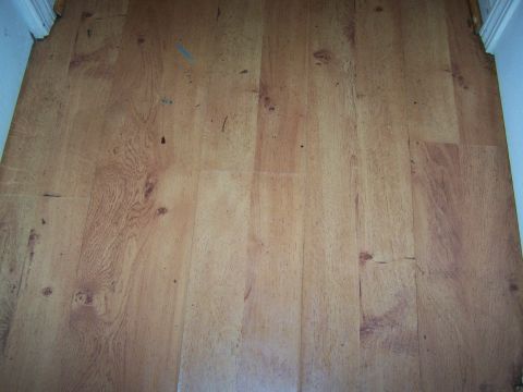 1978 Ford Bronco - The image shows a section of wood-look flooring, likely in a residential setting, with some scuffs and marks.