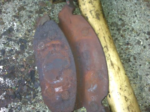 1995 Ford Bronco - Two rusted exhaust pipe sections and a yellow pipe are visible on a gravel surface.