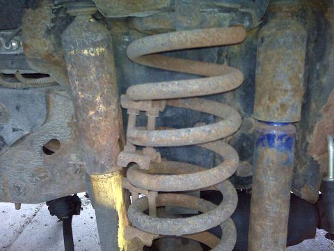 1995 Ford Bronco - The vehicle's suspension shows significant rust on the coil spring and shock absorbers.