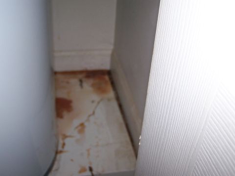 1978 Ford Bronco - A water heater is visible next to a floor with water stains and cracks, adjacent to a white baseboard.