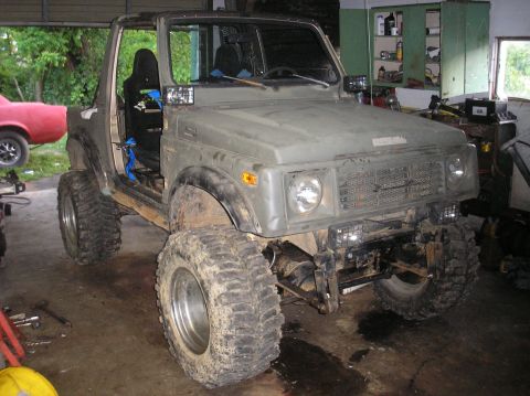 1987 Suzuki Samurai - Modified 1987 Suzuki Samurai parked in a garage, showing its off-road tires and lifted suspension.
