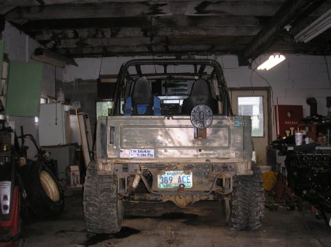 1987 Suzuki Samurai - This heavily modified off-road vehicle is parked inside a cluttered garage with various tools and parts visible.