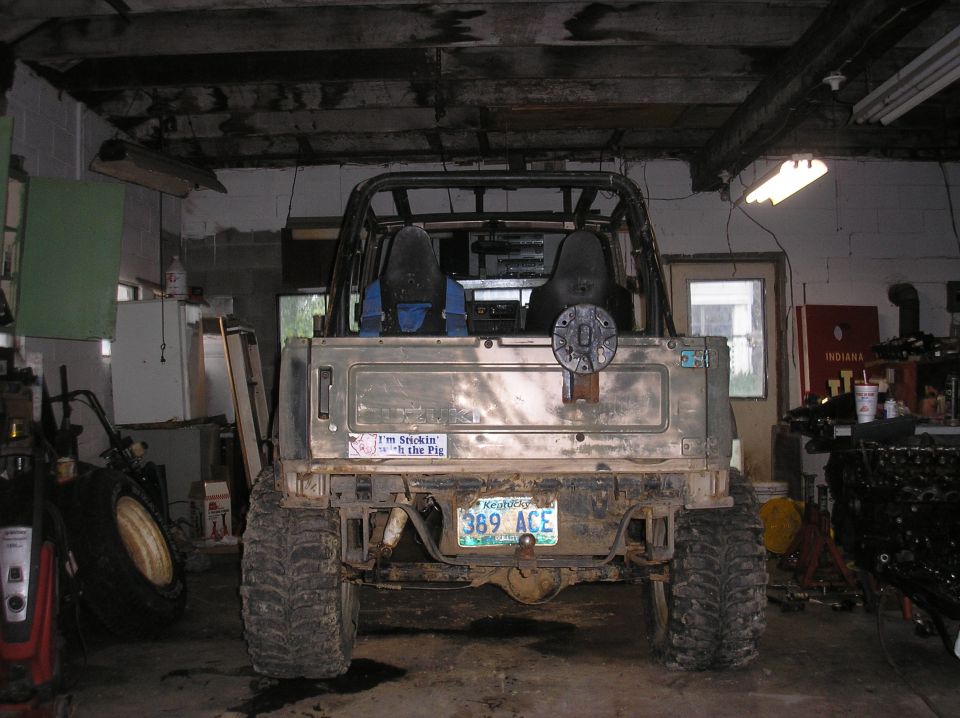 Rear view of a lifted off-road vehicle with large tires, spare tire mount on the tailgate, and a license plate reading '389 ACE'