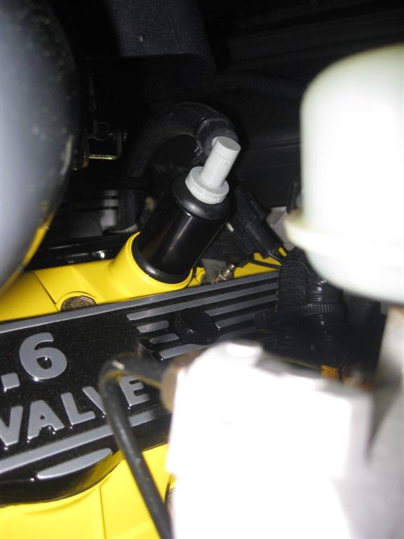 Black oil separator with a gray cap on a yellow engine component labeled "-6 VALVE"