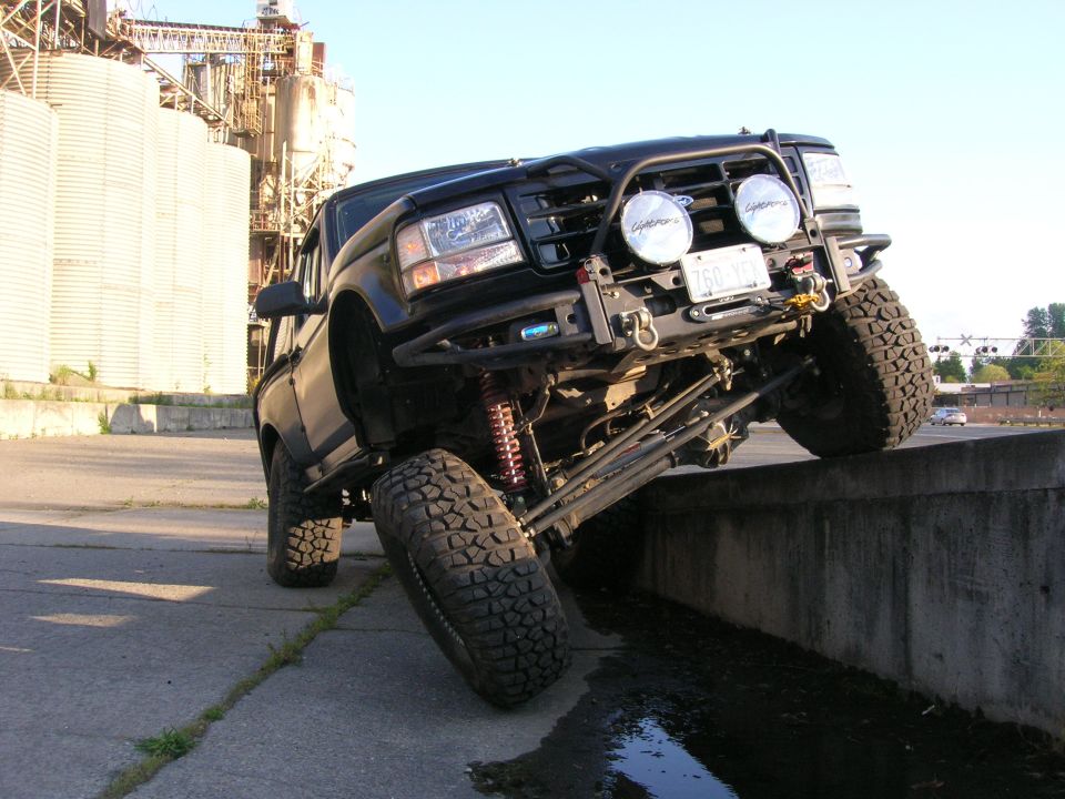 Black pickup truck with lifted suspension, off-roading on a concrete ledge