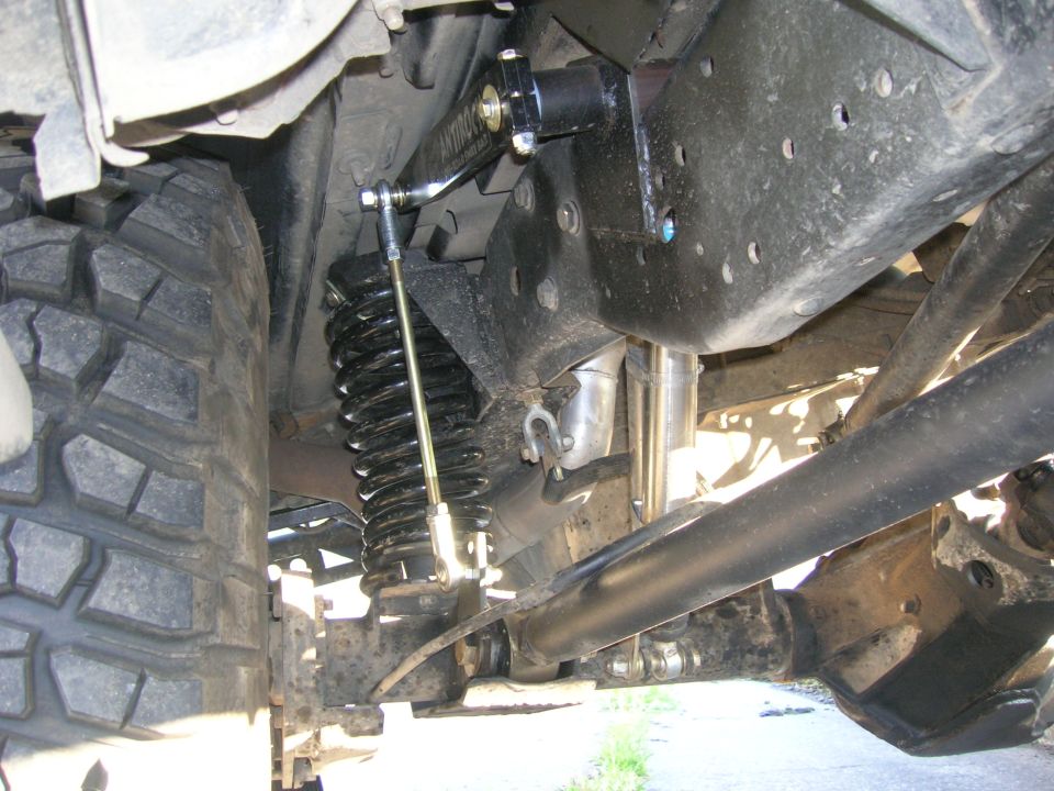 Close-up of a vehicle's rear suspension with a coil spring, shock absorber, and linkage
