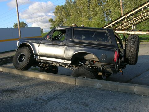 1996 Ford Bronco - This modified 1996 Ford Bronco features an aggressive stance and a rear-mounted spare tire, highlighting its off-road capabilities.
