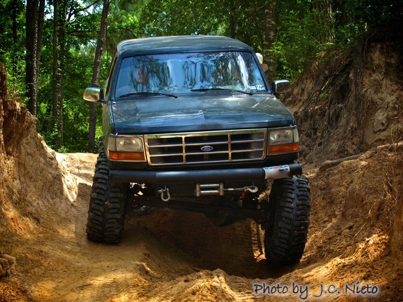 Dark SUV with off-road tires on a dirt path, front view
