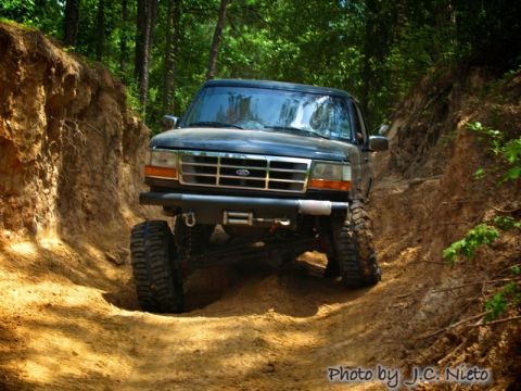 1995 Ford Bronco - Ford Bronco navigates a challenging off-road trail in a wooded area.