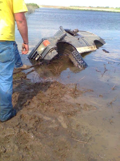 1990 Ford Bronco - A vehicle has become stuck in the water, with only part of it visible above the surface.
