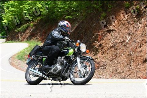 1985 Ford LTD Crown Victoria - A rider on a green Honda motorcycle navigates a curve on a scenic road.