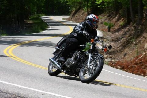 1985 Ford LTD Crown Victoria - A rider navigates a scenic, winding road on a green motorcycle.