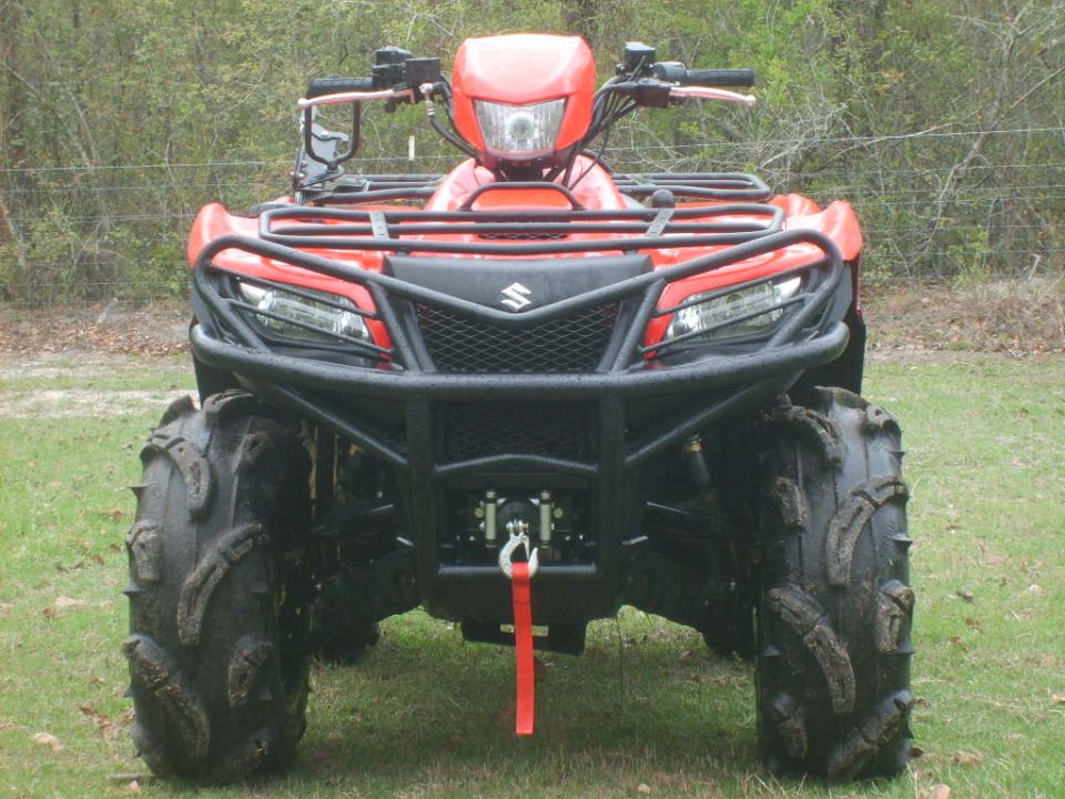 Red Suzuki King Quad ATV, front view, with mud tires and winch on grass