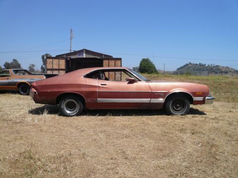 1975 Ford Ranchero - A red 1975 Ford Ranchero sits in a dry, grassy field under a clear blue sky.
