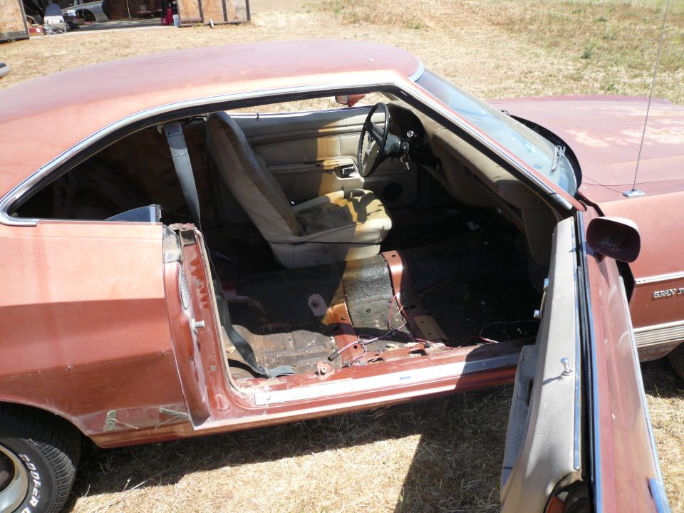 Interior of a 1975 Ford Ranchero, showing worn seats and stripped floor