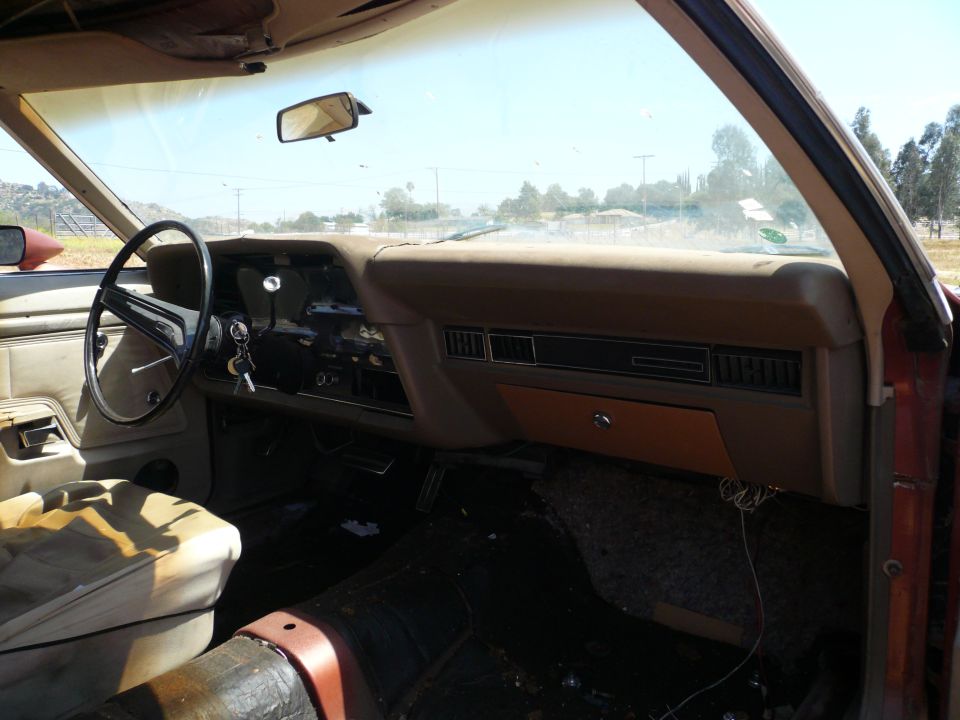 1975 Ford Ranchero interior showing dashboard, steering wheel, and worn driver's seat