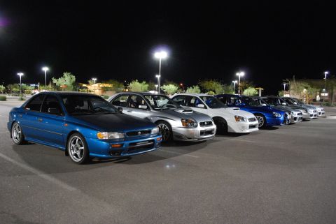 2005 Subaru Impreza - A line of Subaru Imprezas, including a blue sedan in the foreground, parked in a lot at night.