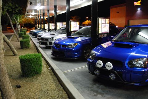 2005 Subaru Impreza - Multiple Subaru Imprezas lined up at a drive-thru restaurant at night.