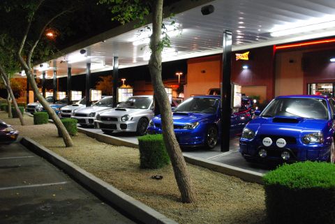 2005 Subaru Impreza - A line of Subaru WRX STi models are parked under the drive-thru canopy of a Sonic restaurant at night.