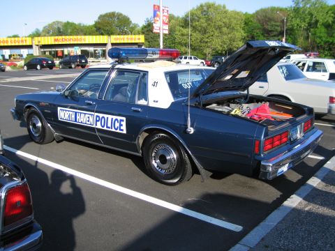 1991 Ford LTD Crown Victoria - dark-blue North Haven Police sedan, unit 41, with its trunk open displaying equipment, parked near a McDonald's.