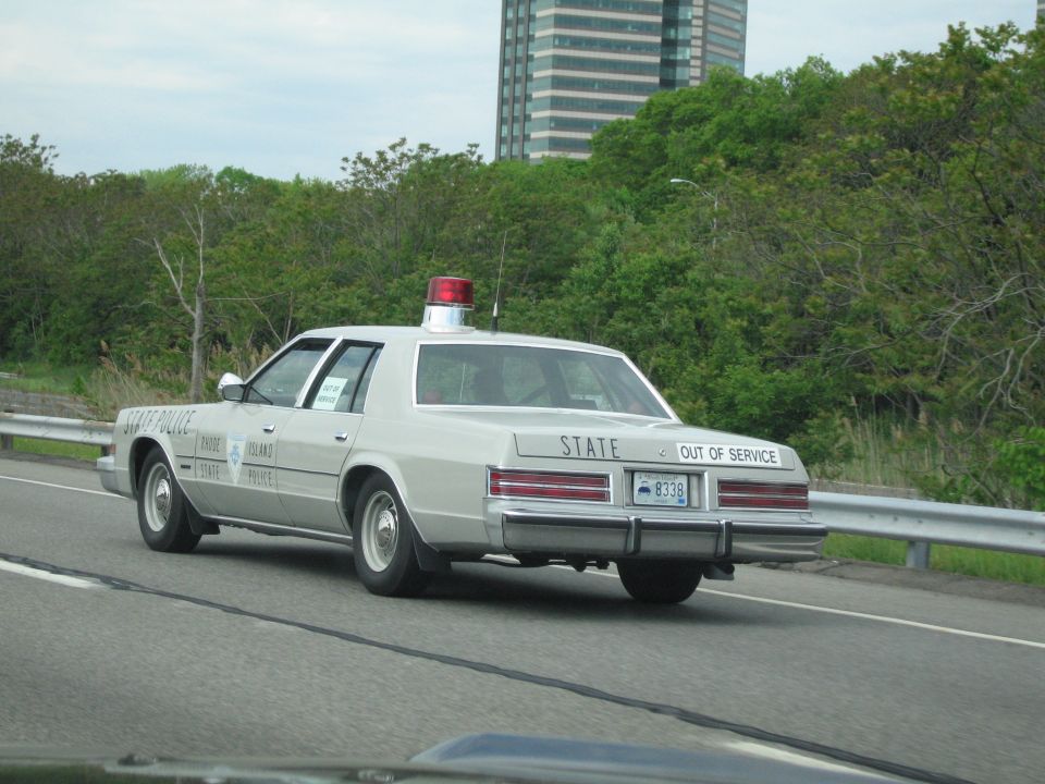 Silver State Police sedan marked OUT OF SERVICE driving past a high-rise