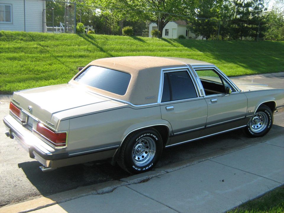 1988 Mercury Grand Marquis parked on a curb, tan exterior with a brown vinyl roof