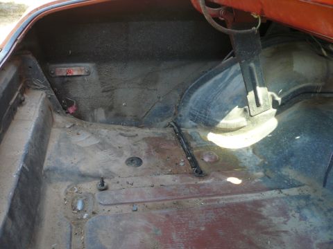 1975 Ford Ranchero - The trunk interior of a red vehicle shows signs of wear and tear, with a watermark at the bottom right.