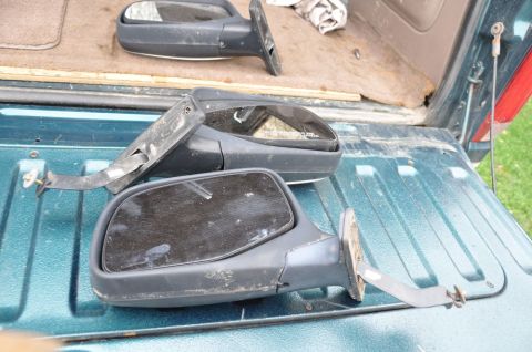 1996 Ford Bronco - Two side mirrors, one damaged, are placed in the back of a teal pickup truck.