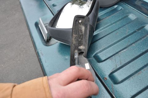 1996 Ford Bronco - A person works on repairing a side mirror, with the truck bed visible in the background.