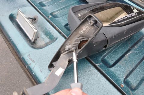 1996 Ford Bronco - Disassembling a side mirror, focusing on the internal housing and screw removal.